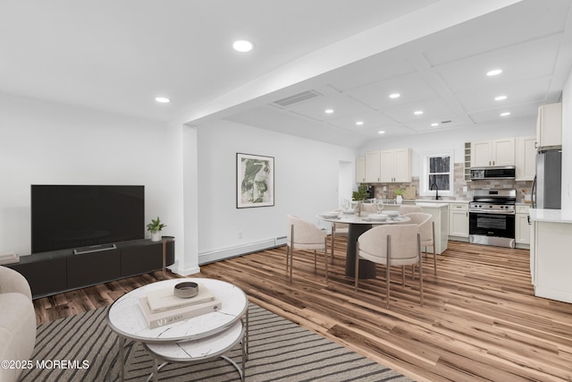 living area with a baseboard heating unit, visible vents, recessed lighting, light wood-style floors, and coffered ceiling