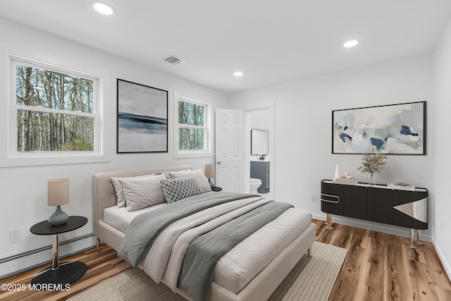 bedroom featuring baseboard heating, wood finished floors, visible vents, and recessed lighting