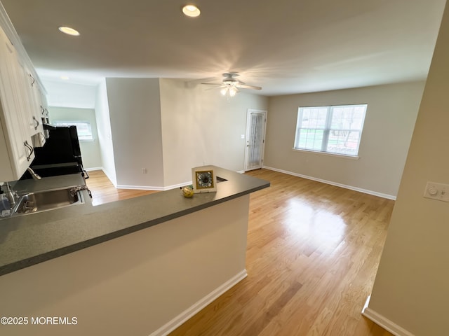 kitchen featuring ceiling fan, dark countertops, baseboards, a peninsula, and white cabinetry