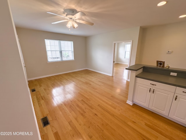unfurnished room with ceiling fan, baseboards, light wood finished floors, and visible vents