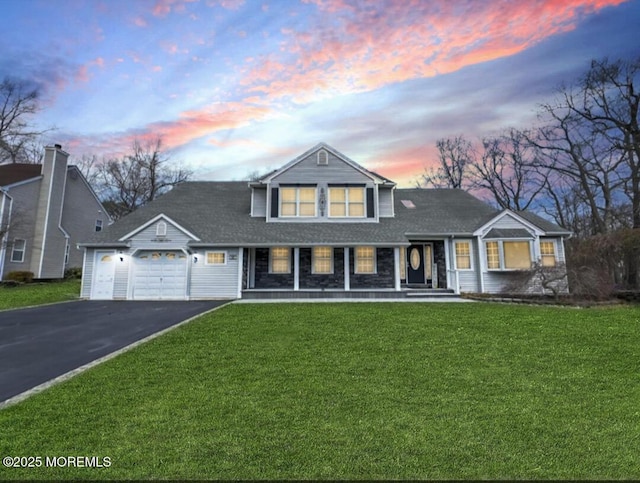 view of front of property featuring a lawn, an attached garage, aphalt driveway, and a porch