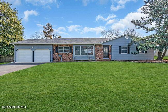 single story home featuring a front lawn, driveway, an attached garage, and brick siding