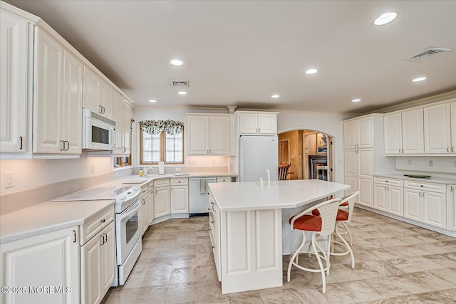 42 Pershing Ave, Sayreville Boro, NJ 08872 - kitchen with white appliances, arched walkways, a kitchen island, recessed lighting, and white cabinets