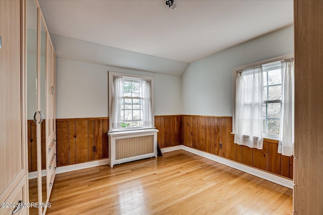 42 Pershing Ave, Sayreville Boro, NJ 08872 - empty room with radiator, light wood-style flooring, wainscoting, vaulted ceiling, and wooden walls