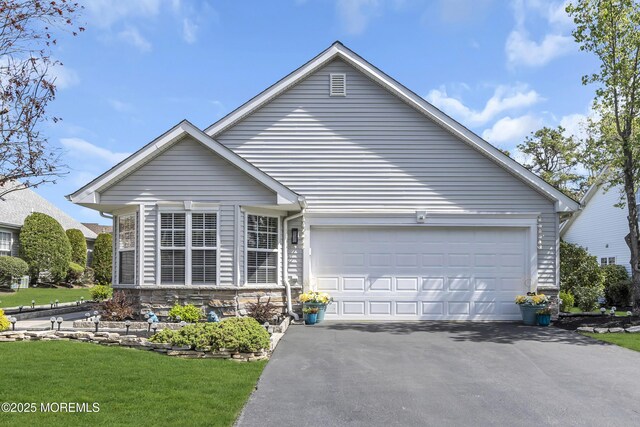 view of front of house with an attached garage, driveway, stone siding, and a front yard
