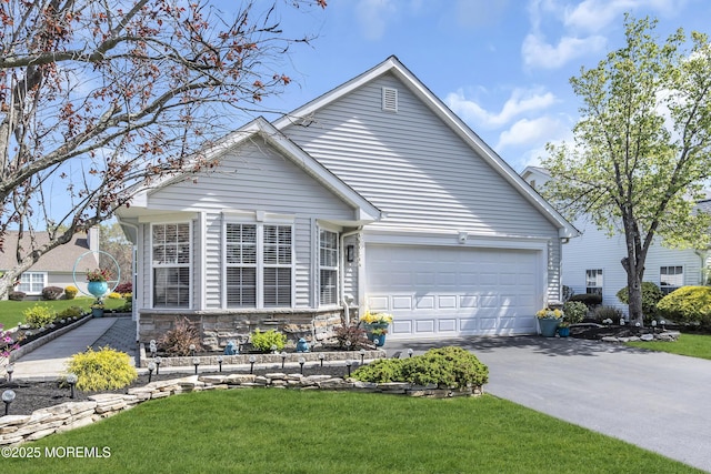 view of front of property featuring an attached garage, driveway, a front yard, and stone siding