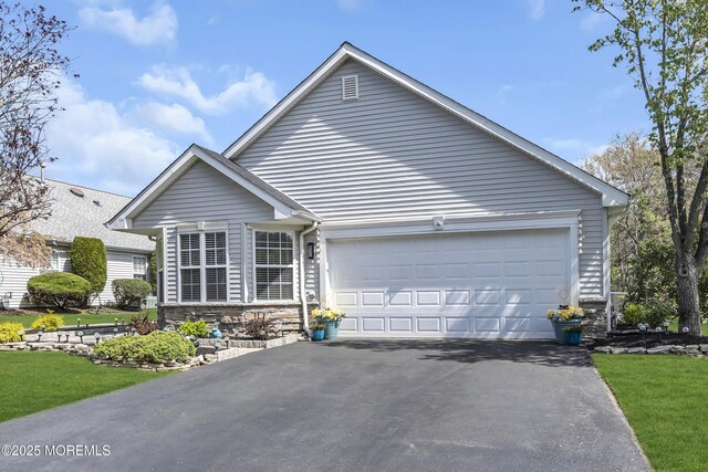 view of front of home featuring an attached garage, driveway, and stone siding