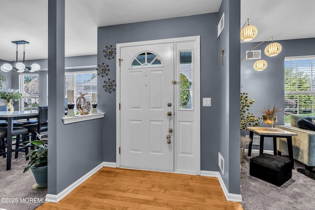 entryway featuring a chandelier, light wood-type flooring, visible vents, and baseboards