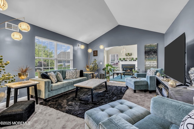 living room featuring a glass covered fireplace, vaulted ceiling, visible vents, and carpet flooring