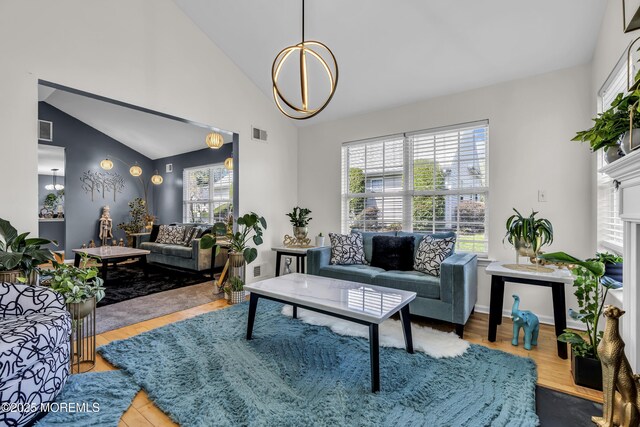 living area with high vaulted ceiling, an inviting chandelier, wood finished floors, and visible vents