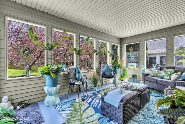sunroom featuring concrete flooring, an outdoor hangout area, wood walls, and a wealth of natural light