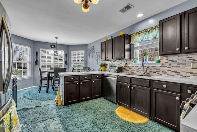 kitchen featuring dark brown cabinets, visible vents, a sink, a peninsula, and appliances with stainless steel finishes