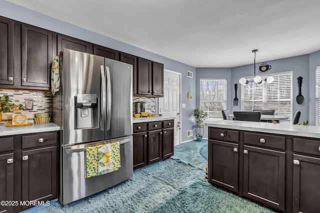 kitchen with stainless steel refrigerator with ice dispenser, light countertops, dark brown cabinetry, and light colored carpet