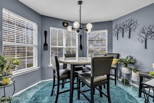 dining space featuring baseboards, a chandelier, and carpet