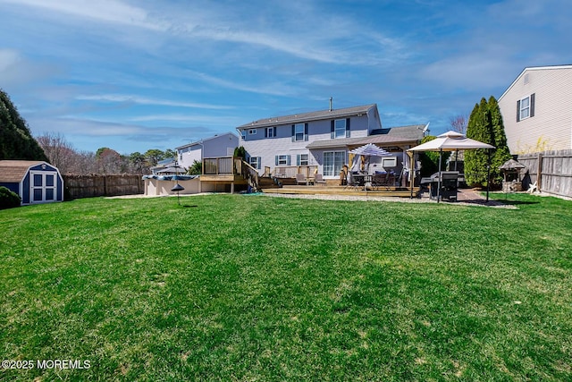 rear view of house with an outbuilding, a wooden deck, a storage shed, a fenced backyard, and a gazebo