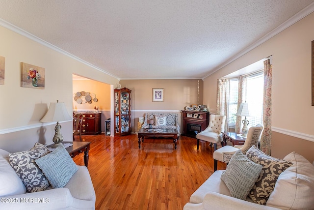 living room featuring a textured ceiling, ornamental molding, and wood finished floors