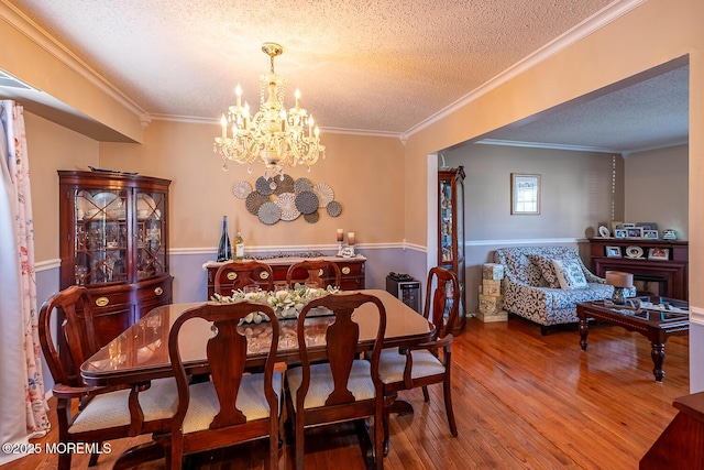 dining room featuring crown molding, an inviting chandelier, wood finished floors, and a textured ceiling