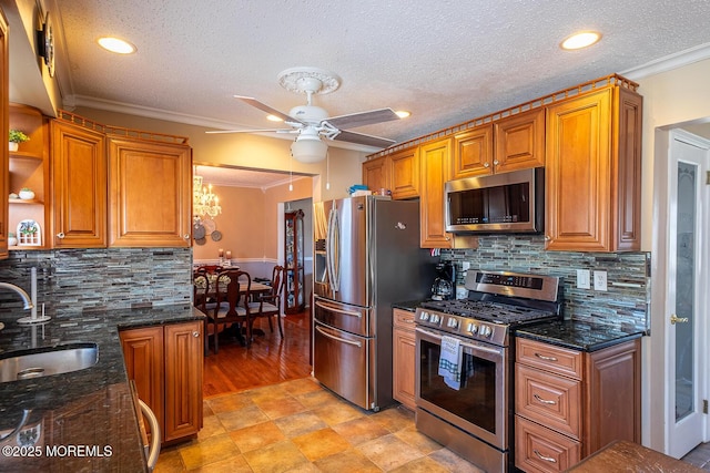 kitchen with a sink, a ceiling fan, crown molding, and stainless steel appliances
