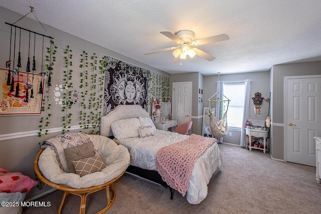 carpeted bedroom featuring a ceiling fan and a textured ceiling