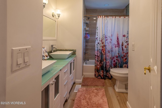 bathroom with shower / bath combo, a sink, toilet, double vanity, and wood finished floors