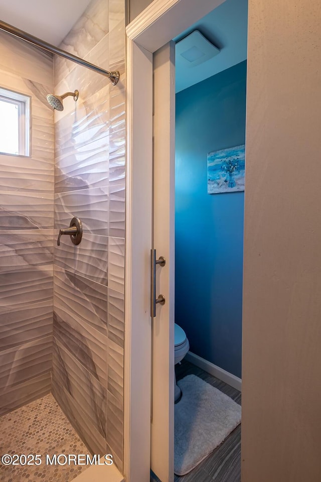bathroom featuring a tile shower and toilet