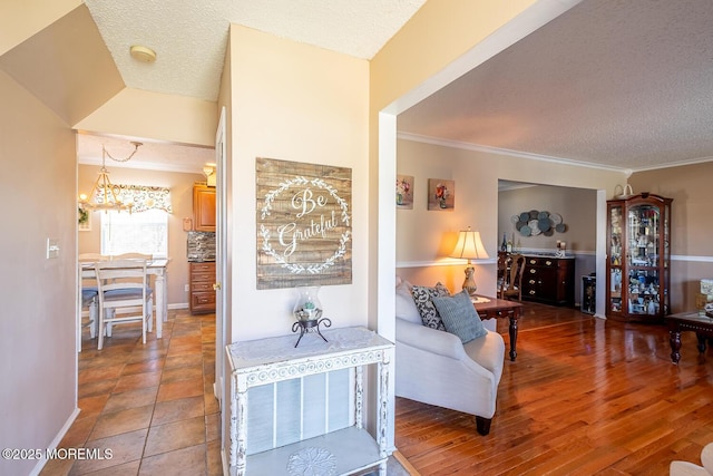 living room featuring a textured ceiling, ornamental molding, and wood finished floors