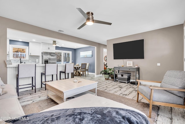 living room with visible vents, baseboards, and ceiling fan