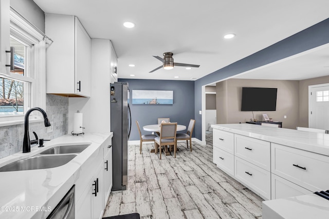 kitchen featuring a sink, ceiling fan, light wood-type flooring, freestanding refrigerator, and white cabinetry