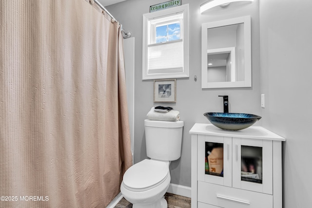 bathroom featuring a shower with shower curtain, vanity, baseboards, and toilet