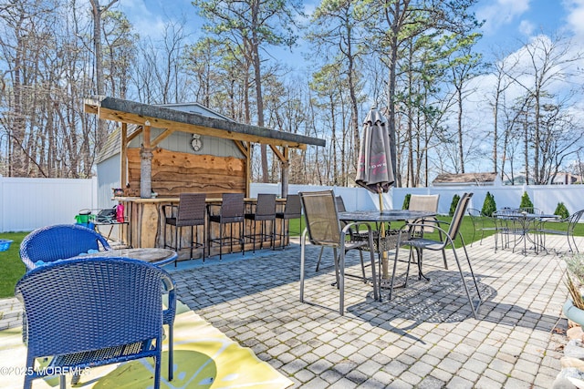 view of patio with outdoor dining space, fence, and outdoor dry bar