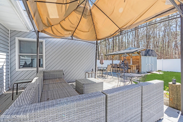 view of patio / terrace featuring an outbuilding, a fenced backyard, a wooden deck, and outdoor dining area
