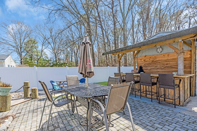 view of patio / terrace with a fenced backyard, outdoor dining space, and outdoor dry bar