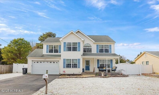 view of front of house featuring driveway, covered porch, and fence