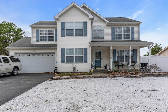 traditional-style home featuring covered porch, fence, a garage, and aphalt driveway