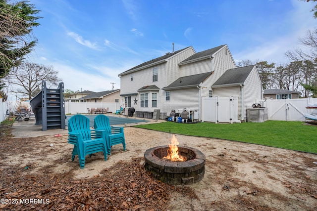 rear view of property with a fire pit, a gate, a patio area, a fenced backyard, and a yard