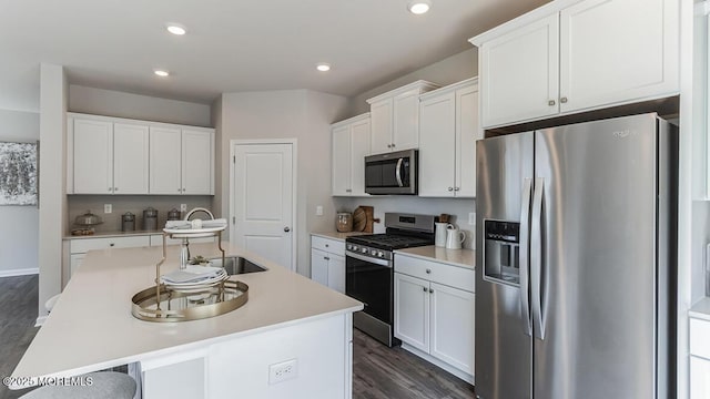 kitchen featuring white cabinetry, a sink, stainless steel appliances, and a kitchen island with sink
