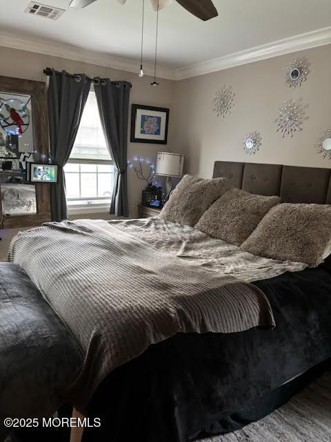 bedroom featuring wood finished floors, visible vents, and ornamental molding