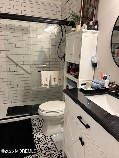 full bathroom featuring toilet, vanity, a shower stall, and tile patterned flooring