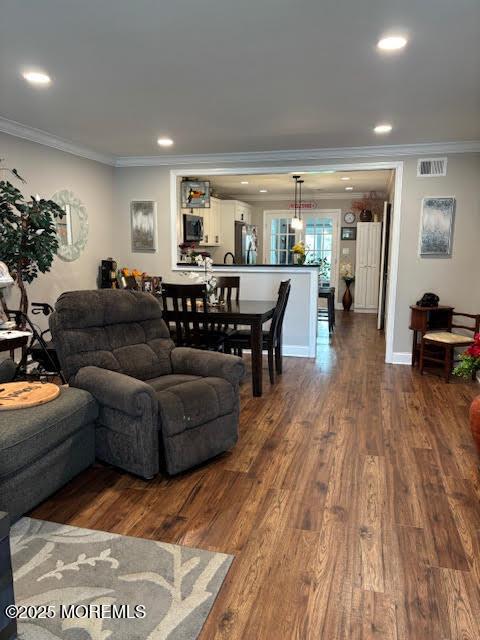 living area with dark wood-type flooring, visible vents, crown molding, and recessed lighting