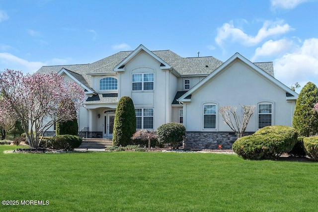 traditional-style house with stucco siding, stone siding, and a front lawn
