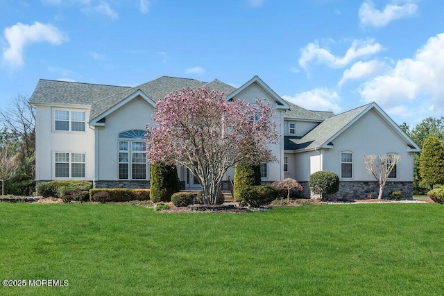 view of front of property with a front yard, stucco siding, and stone siding