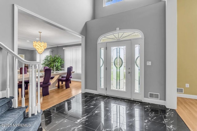 entrance foyer featuring a chandelier, stairway, visible vents, and baseboards