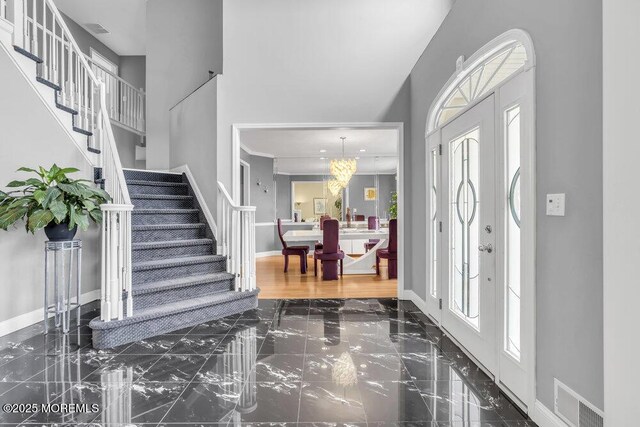 entryway featuring a towering ceiling, visible vents, stairway, marble finish floor, and baseboards