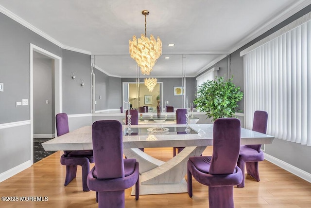dining space with crown molding, baseboards, a notable chandelier, and wood finished floors