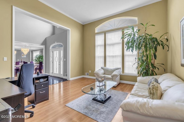living area with light wood-type flooring, crown molding, baseboards, and a notable chandelier