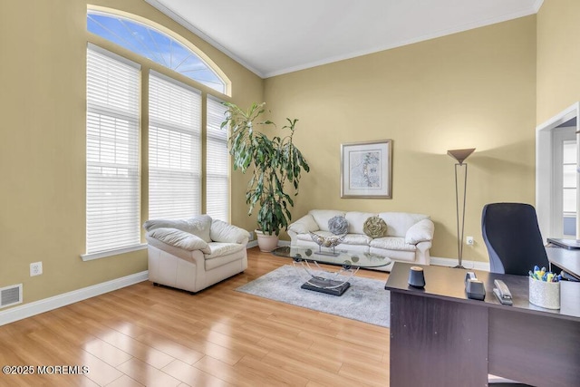 living room featuring visible vents, ornamental molding, baseboards, and wood finished floors