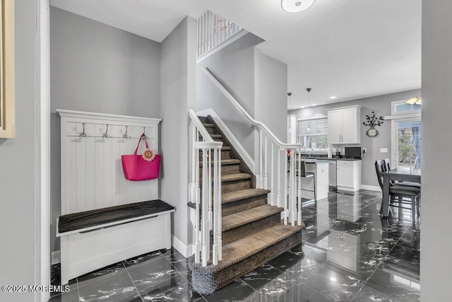 stairway featuring marble finish floor and baseboards