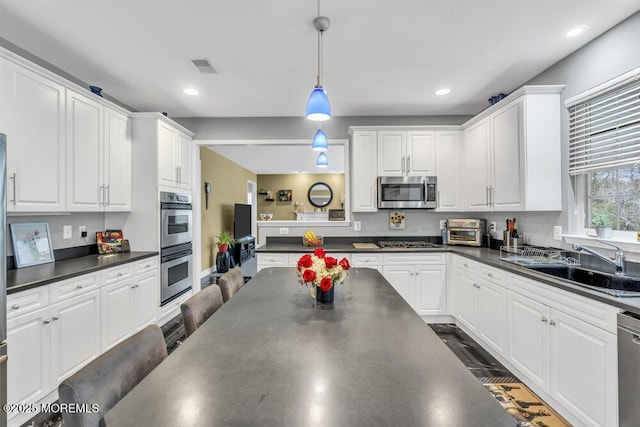 kitchen featuring appliances with stainless steel finishes, a sink, and dark countertops