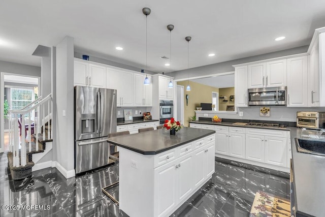 kitchen with dark countertops, appliances with stainless steel finishes, marble finish floor, and white cabinetry