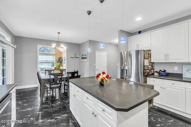 kitchen featuring a center island, dark countertops, marble finish floor, and stainless steel appliances